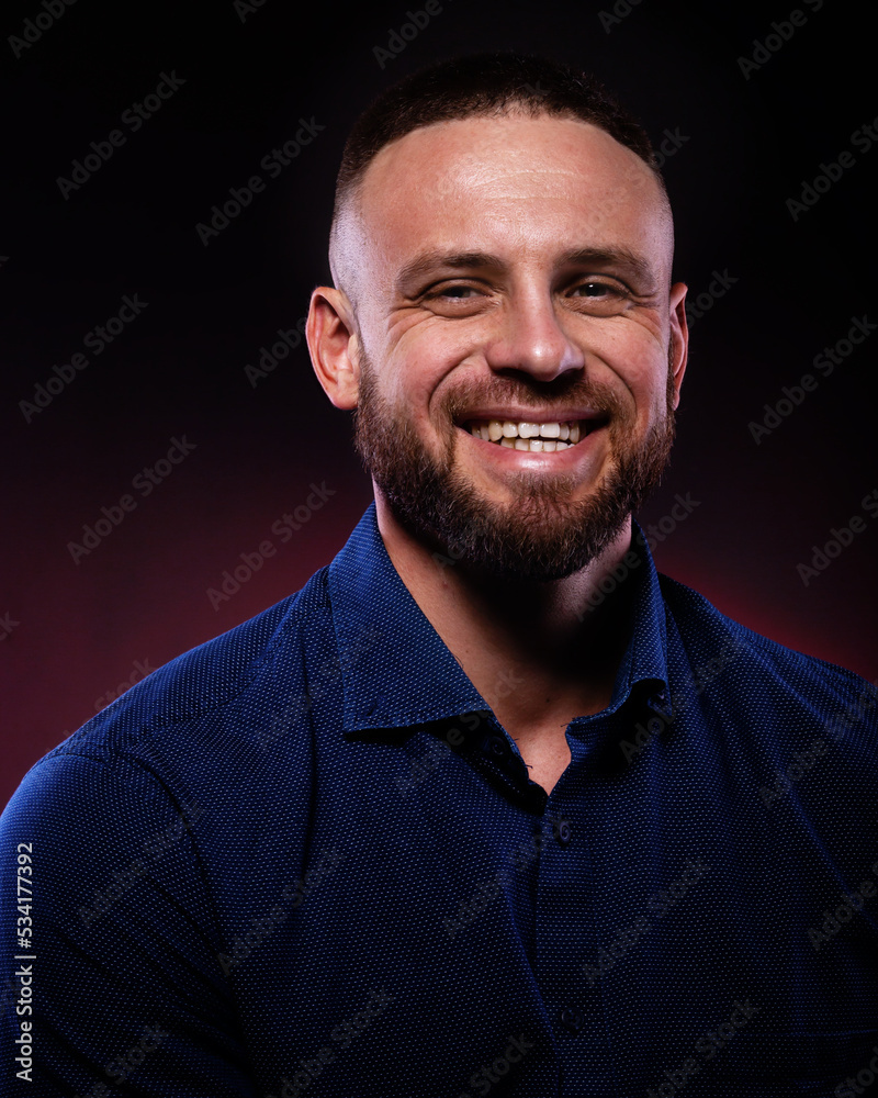 Portrait of smiling handsome man in blue shirt. Posing in studio on dark red background Portrait of smiling handsome man in blue shirt. Posing in studio on dark red background