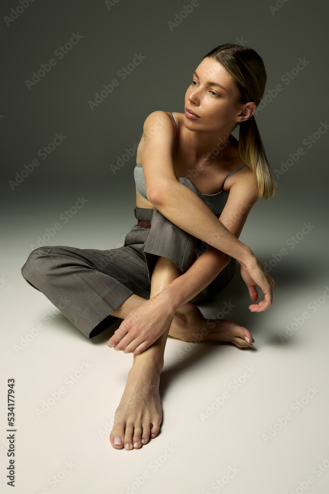 Portrait of beautiful woman posing in casual comfortable clothes, top and pants isolated over grey background