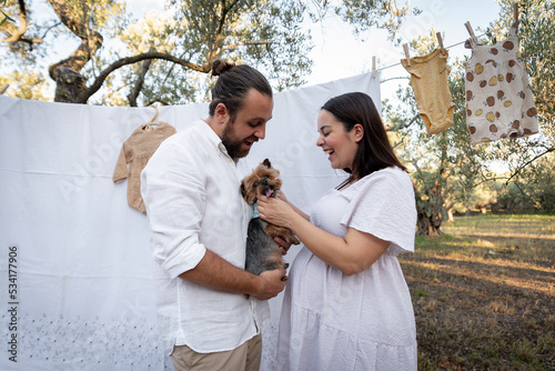 Happy young couple with their dog, expecting baby. Pregnancy concept.