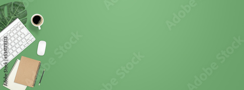 Flat lay work desk table with computer , book , coffee on green pastel color tone background include empty space for product or text graphic advertise