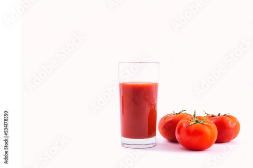 Tomato juice in a glass and ripe tomatoes on a white background