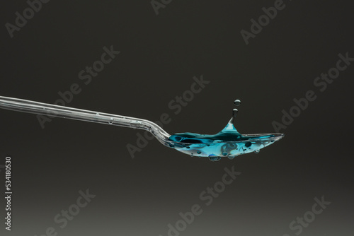 lastic spoon with water drops frozen at high speed showing surface tension and droplet splash structure photo