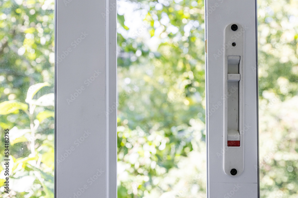 Close-up of a double-glazed balcony frame with a latch and fastening for safe ventilation. Single-sided window handle. House door and window repair concept
