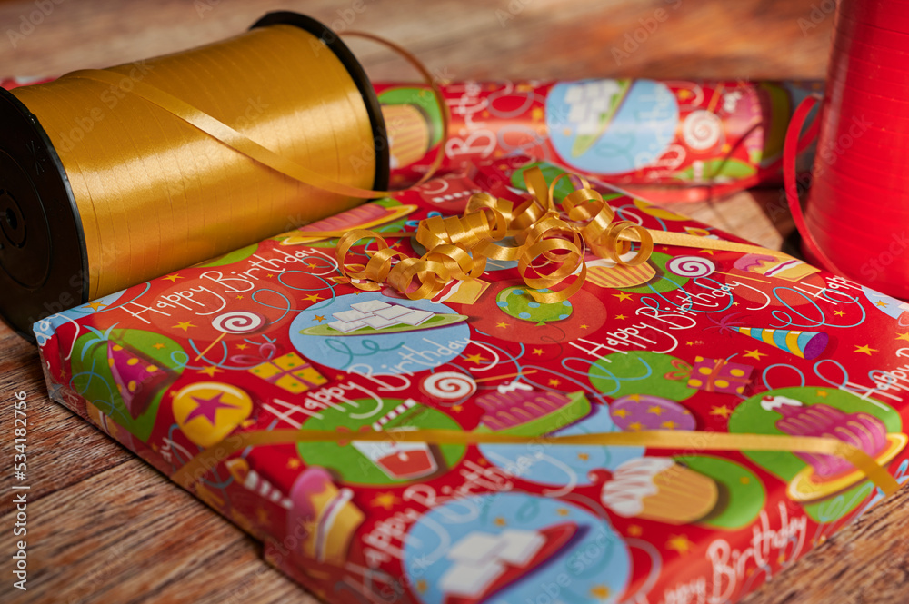 Wrapped birthday gift with wrapping material on a wooden table. Wrapped birthday gift with wrapping material on a wooden table.