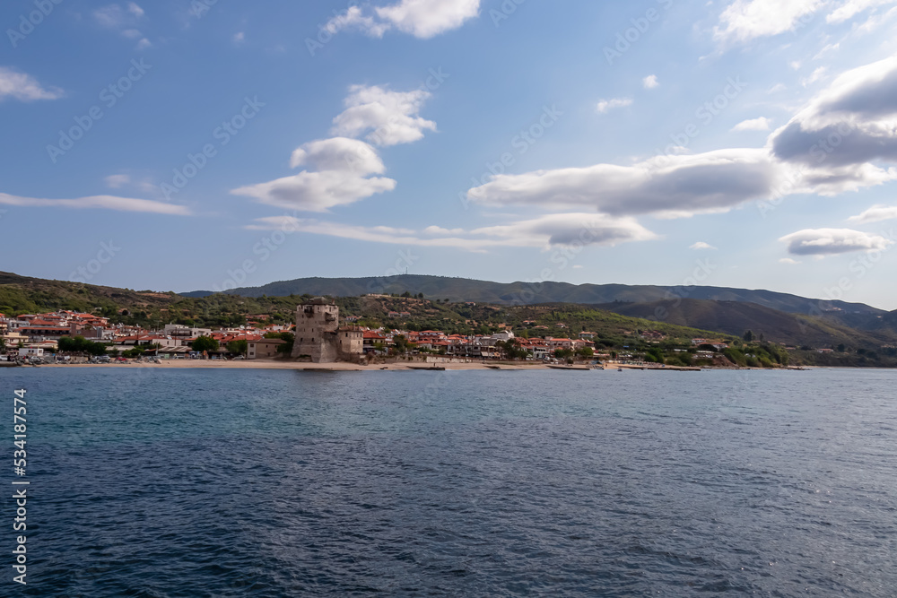 Panoramic view from boat tour on Ouranoupolis town nd ancient Tower of Ouranoupolis on peninsula Mount Athos (Again Oros), Chalkidiki, Central Macedonia, Greece, Europe. Mediterranean Aegean Sea
