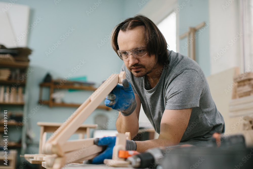 A carpenter makes wooden toys in a carpentry workshop. Making a bed carousel. A carpenter makes wooden toys in a carpentry workshop. Making a bed carousel.