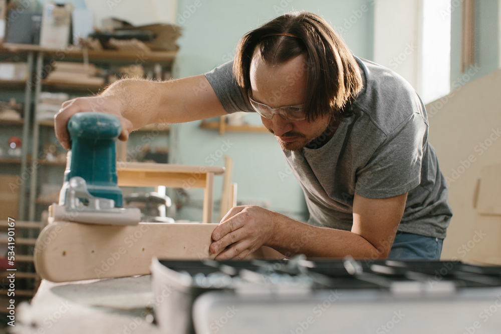 Worker grinds the wood of grinding machine. Worker grinds the wood of grinding machine.