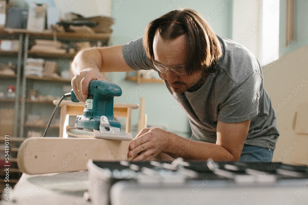 Worker grinds the wood of grinding machine.