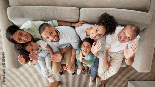 Family, children and wave with a portrait of kids, grandparents and parents sitting on a sofa in the living room of their home from above. Happy, smile and love with a senior man, woman and relatives photo