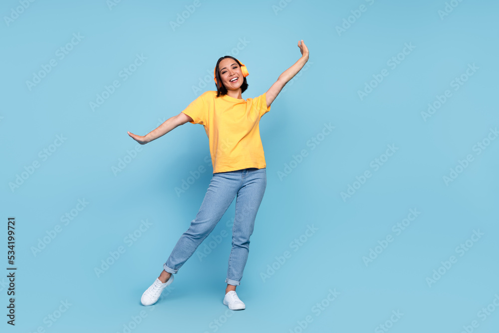 Full length photo of young cute korean woman celebrate dancer empty space headphones advert disco hands up positive vacation isolated on blue color background