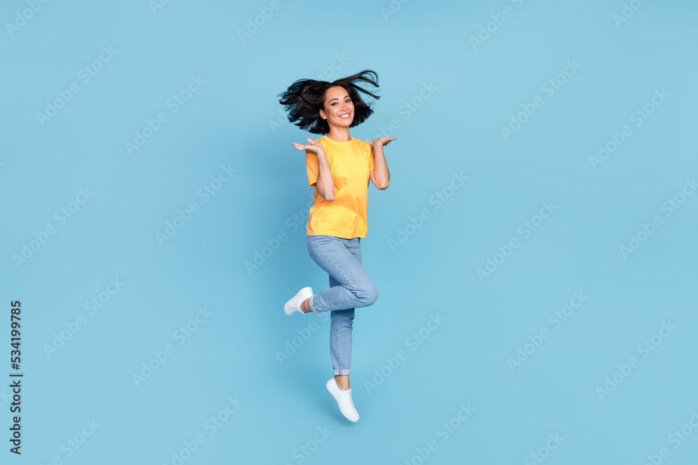 Full body portrait of overjoyed adorable lady jumping good mood isolated on blue color background Full body portrait of overjoyed adorable lady jumping good mood isolated on blue color background