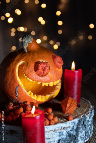 Smiling pumpkin, rowan berries and red candles with bokeh. Close-up