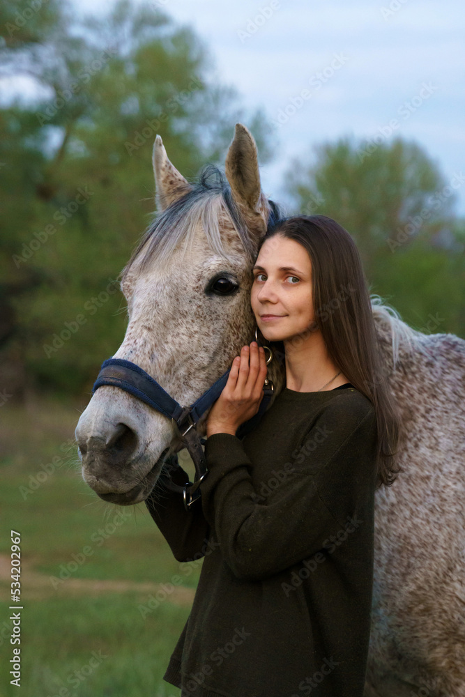 Obraz premium Girl hugging a fleabitten grey horse and looking at the camera