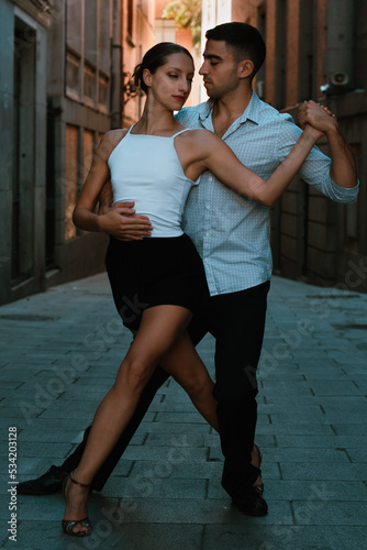 Couple dancing Tango. Boy in a suit and girl in shorts and a white t-shirt. Tango position.