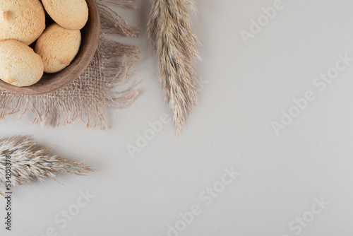 Bowl of cookies next to needlegrass stalks on marble background photo