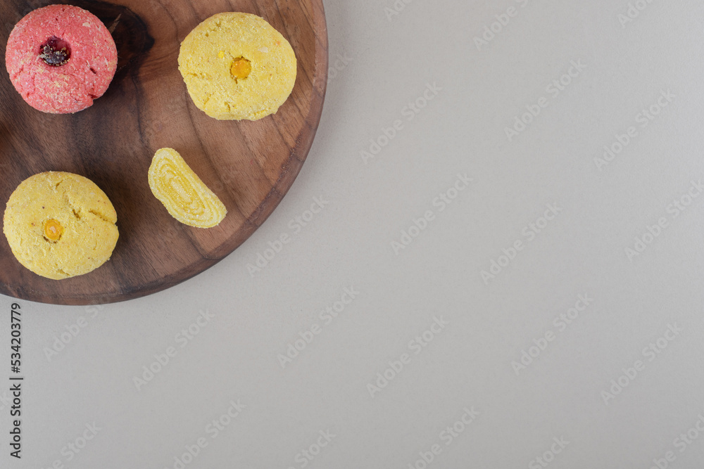 Arrangement of marmelades and cookies on a wooden board on marble background