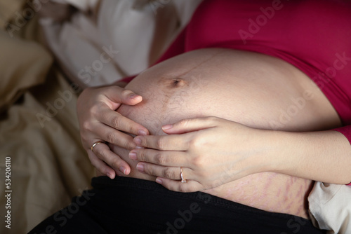 Pregnant woman touching her belly in the bed. Pregnancy, motherhood, and expectation