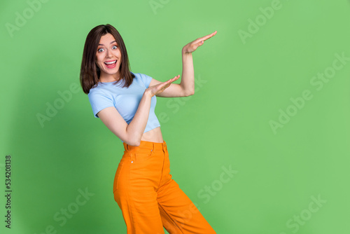 Profile photo of cheerful satisfied girl arms make moves dance empty space isolated on green color background