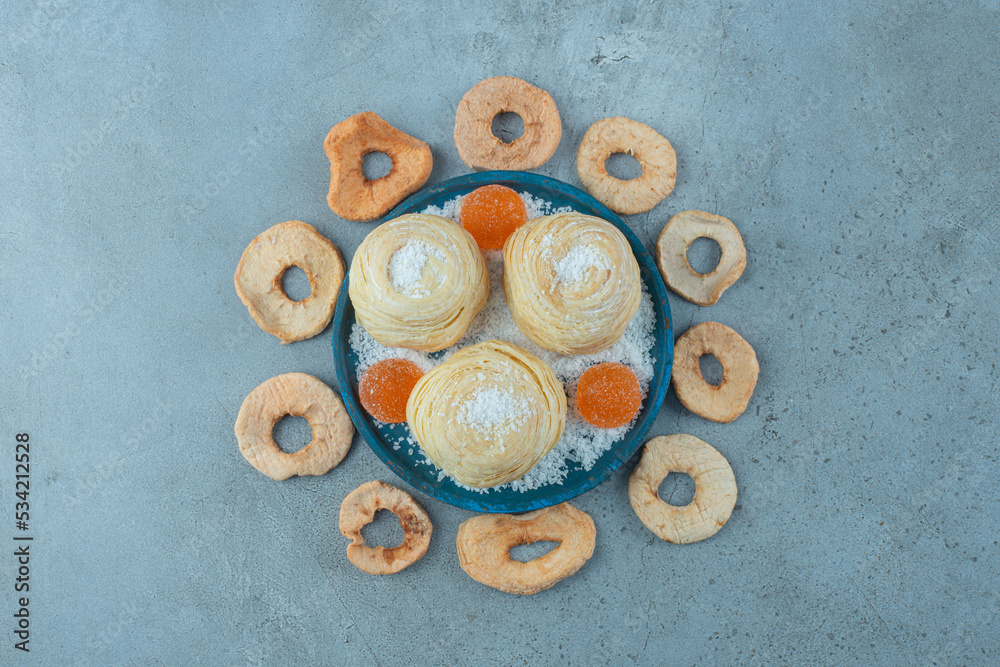 Platter of cookies and marmelades surrounded with dried apple slices on marble background