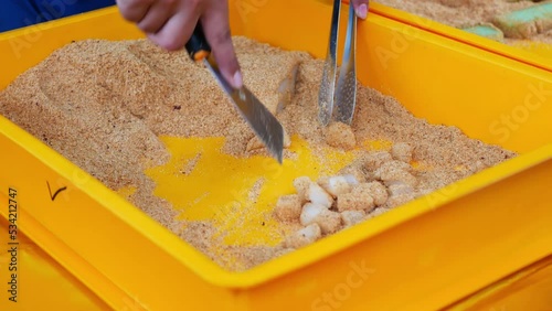 Close-up view of a hawker making muah chee street food, it is a steamed sticky dough basically made of glutinous flour, cut in small pieces and coated with sugar and fine or crushed roasted peanuts photo