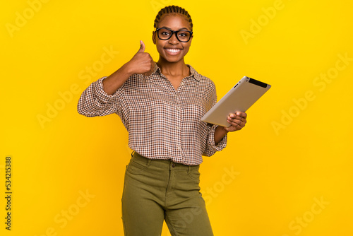 Photo of sweet positive woman wear plaid shirt eyewear reading modern gadget thumb up isolated yellow color background