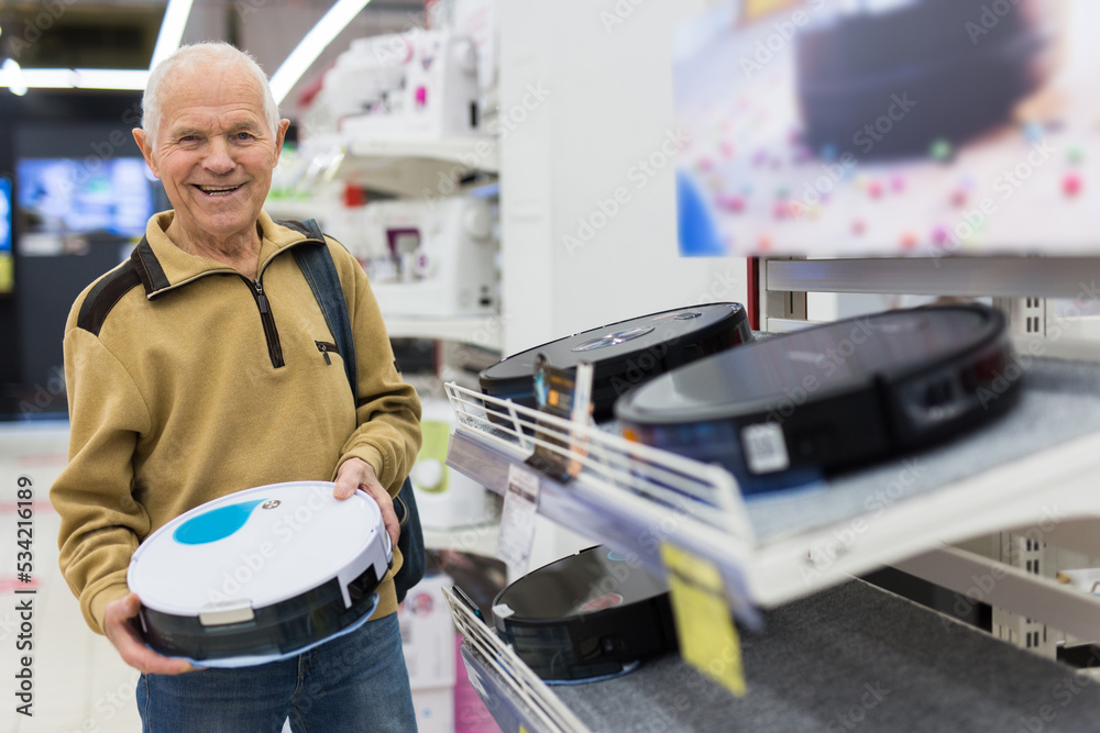 senor man pensioner buying Robotic vacuum cleaner in showroom of electrical appliance store