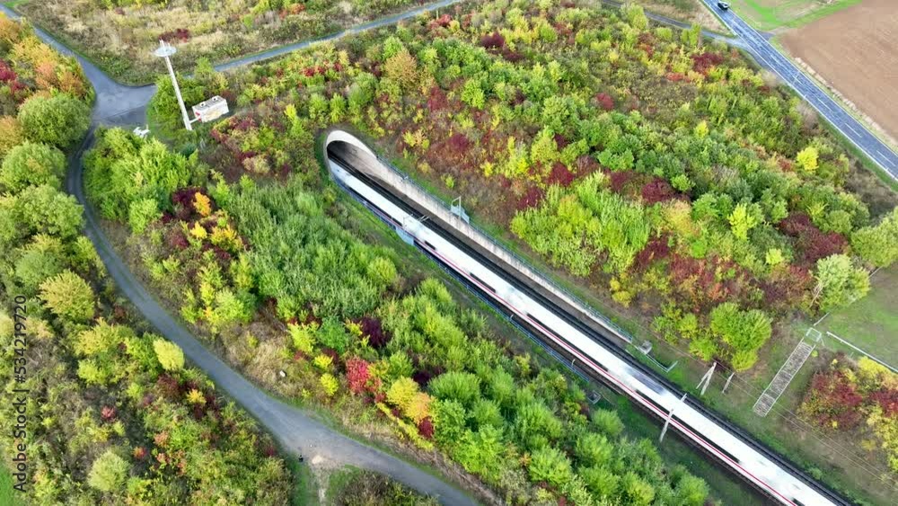 Highspeed train passing the entrance of a tunnel - aerial view from above, tracking shot
