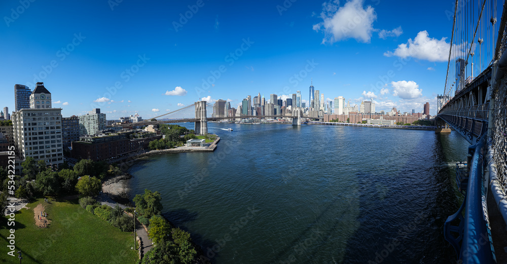 Beautiful view during a sunny day from Manhattan Bridge to Brooklyn Bridge and downtown Manhattan landmark skyscraper office building. Travel to America. New York, 2022.