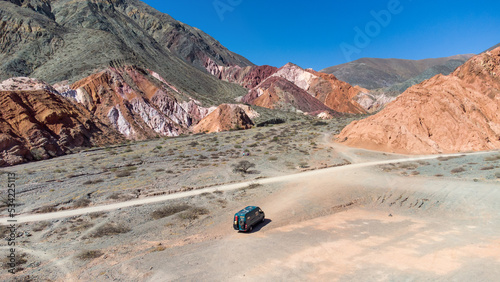 A 4x4 campervan next to mountains of 7 colors. Next to Purmamarca, Los Colorados in the Argentine Puna. photo