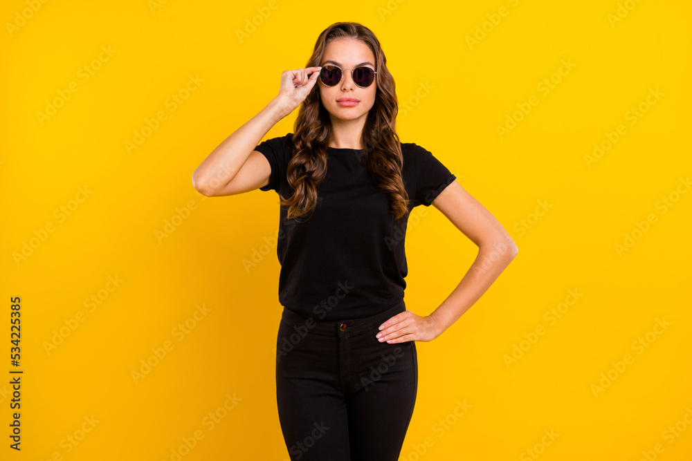 Photo of serious confident young woman wear black outfit arm dark eyeglasses isolated yellow color background Photo of serious confident young woman wear black outfit arm dark eyeglasses isolated yellow color background