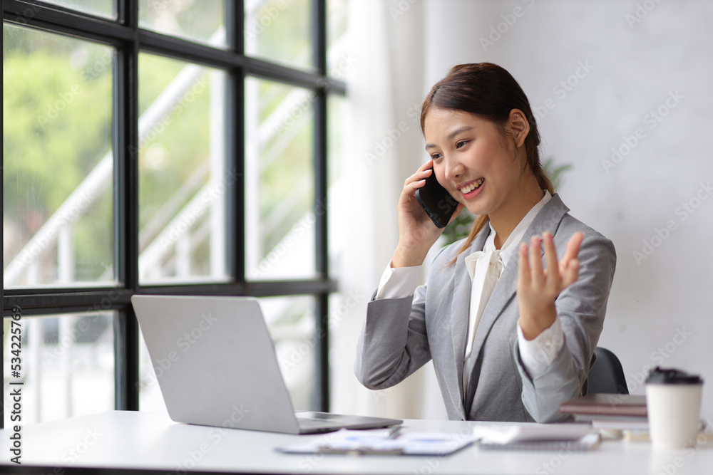 Businesswoman in home office is using a mobile phone to talk to a business partner. Businesswoman in home office is using a mobile phone to talk to a business partner.