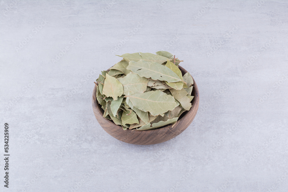 Dry green bay leaves in a rustic cup Dry green bay leaves in a rustic cup