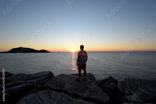 silhouette d'homme regardant un coucher de soleil coloré et vue sur une île - Corse