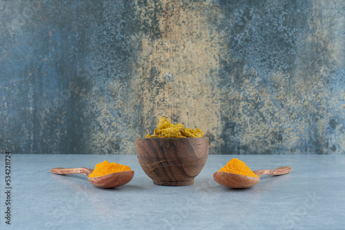 Curcumin beans in a wooden cup with blended powder in wooden spoons