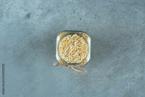 Noodle grains in a glass jar on blue background