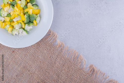 Small portion of pepper and broccoli salad on a piece of fabric on marble background