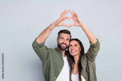Portrait of attractive amorous cheerful couple hugging showing heart symbol amour isolated over grey pastel color background