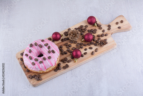 Wooden tray with donut, coffee beans, pine cones and christmas decorations on white background