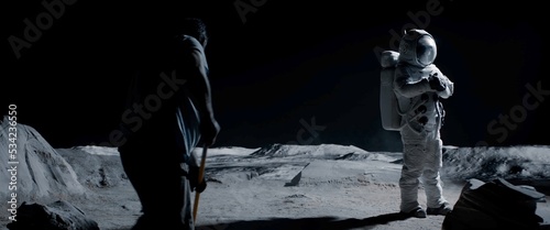 Behind the scenes, actor wearing astronaut suit waiting while film crew decorator straightens lunar surface. Virtual production with LED screens