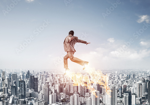 Fotografering Businessman in suit and aviator hat flying in sky