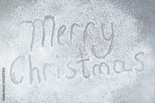 "Merry Christmas" written in a scattered pile of coconut powder on marble background