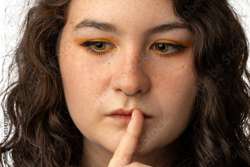 Young woman with finger to mouth as if to say be quiet