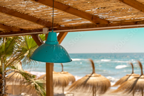 Private beach closed with deckchair and umbrellas tided up. Waves  wind and vintage lamp in the decor. 