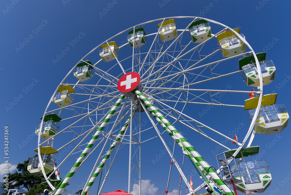 Ferris wheel with Swiss flag at village of Ascona, Canton Ticino, on a sunny summer day. Photo taken July 24th, 2022, Ascona, Switzerland.