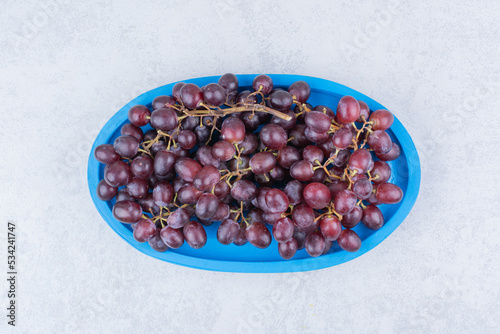 Fresh sweet grapes in blue plate on white background