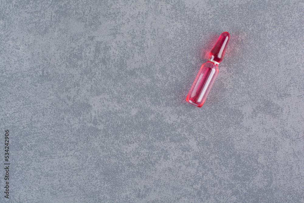 Naklejka premium Red medical ampoule on marble background