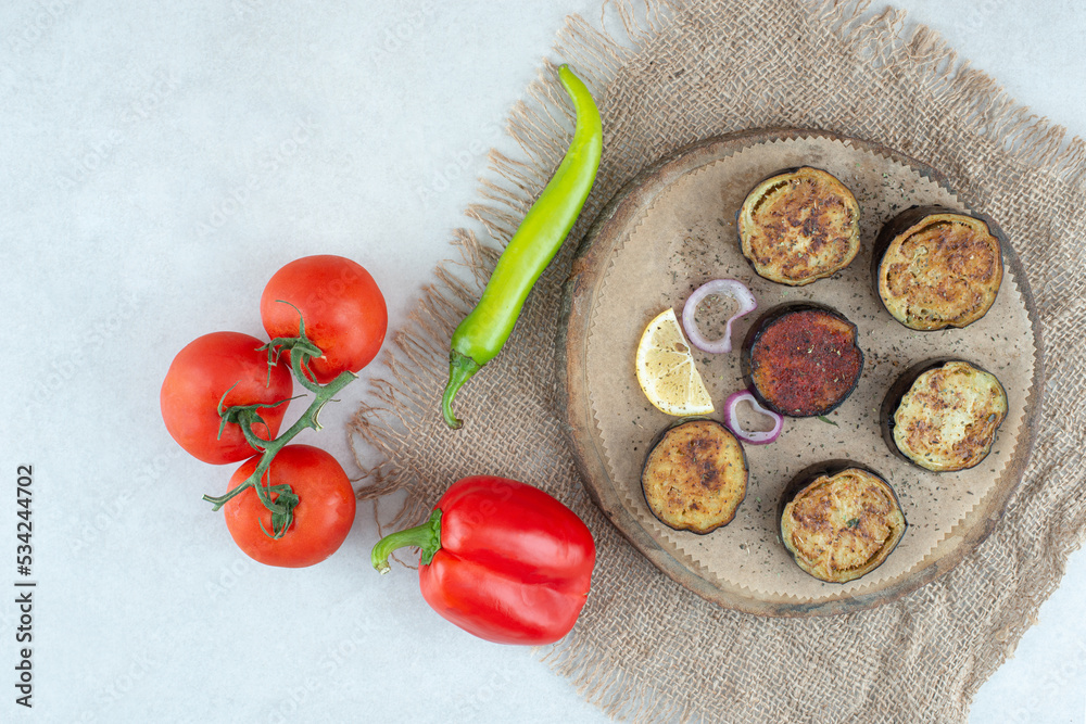 A wooden plate of sliced eggplant and tomatoes A wooden plate of sliced eggplant and tomatoes