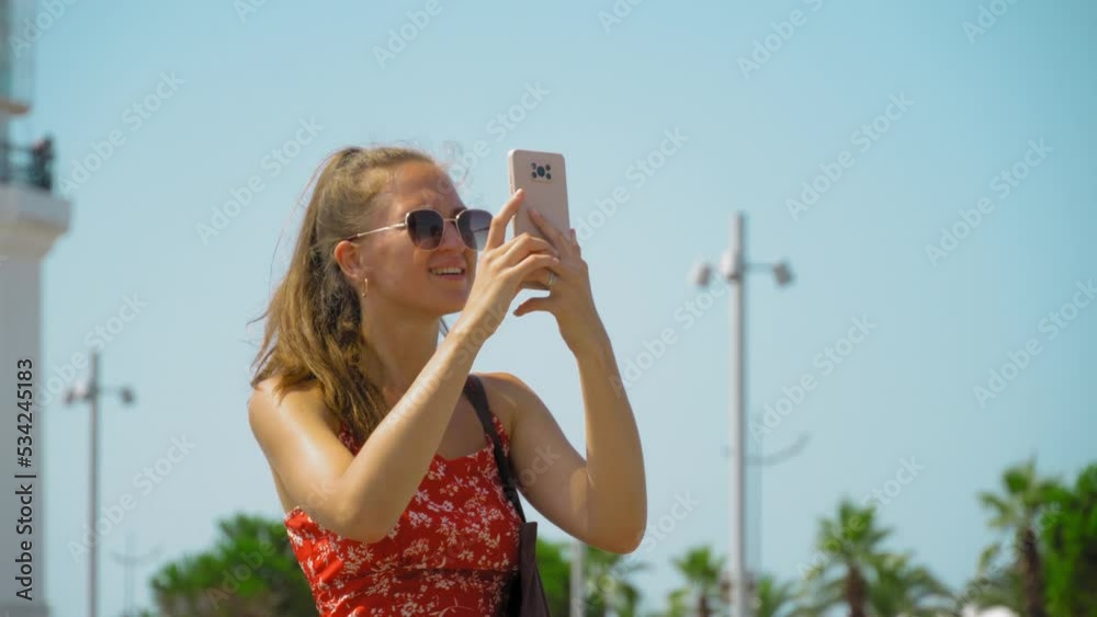 photographer girl holds in her hands mobile phone photographing on smartphone modern city, tourist shooting on camera against background of Gorord architecture, internet online concept