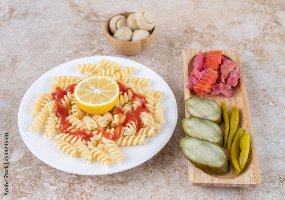 Pickle tray and mushroom bowl accompanied with pasta platter on marble background
