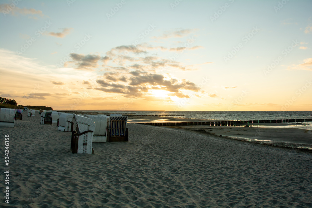 Sunset over the sea with beach chairs on the sandy beach